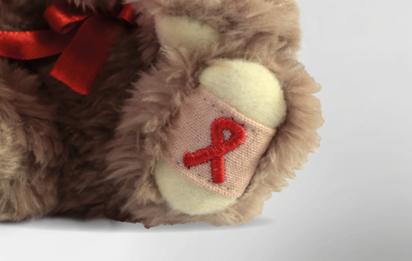 Detailansicht der gestickten AIDS-Schleife am Fuß des AIDS-Bären