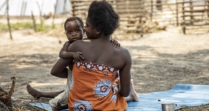 Eine Mutter sitzt mit ihrem Baby auf dem Boden im Camp Mutua in Mosambik